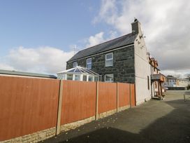 A stone and plaster house with a conservatory behind a wooden fence at Bwthyn Y Mor in Tal-Y-Bont