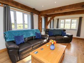 A living room with two black leather sofas a wooden coffee table and windows with grey curtains at Yr Adfa in Llangeitho near Tregaron