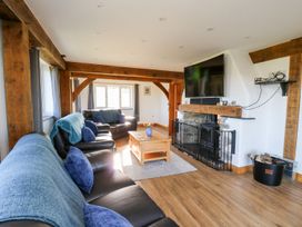 A living room with leather sofas a wooden coffee table a TV mounted above a stone fireplace and wooden beams at Yr Adfa in Llangeitho near Tregaron