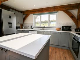 A kitchen with gray cabinets white countertops wooden beams and appliances at Yr Adfa Llangeitho near Tregaron