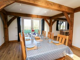 A dining room with a long table set for eight people and wooden beams at Yr Adfa in Llangeitho near Tregaron