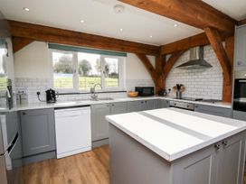A kitchen with grey cabinets a white dishwasher wooden beams and a white countertop at Yr Adfa in Llangeitho near Tregaron