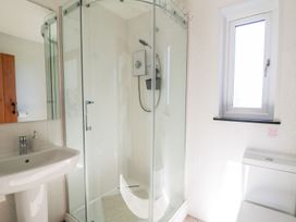 A bathroom with a glass shower enclosure a white pedestal sink and a toilet near a window at Yr Adfa in Llangeitho near Tregaron