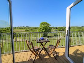 A balcony with a small wooden table and two chairs overlooking green fields and trees at Yr Adfa in Llangeitho near Tregaron