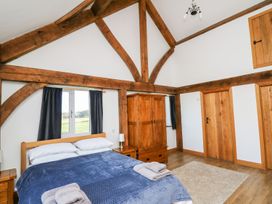 A bedroom with wooden beams a bed with blue cover a wardrobe and wooden doors at Yr Adfa in Llangeitho near Tregaron