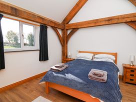 A bedroom with a wooden bed frame covered with a blue blanket and two folded towels on top at Yr Adfa in Llangeitho near Tregaron