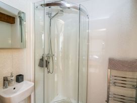 A bathroom with a glass corner shower enclosure a white sink with a faucet a mirror cabinet above the sink and a chrome towel rack with a towel at Yr Adfa Llangeitho near Tregaron