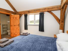 A bedroom with wooden beams blue bedspread on the bed and an open door leading to a bathroom at Yr Adfa in Llangeitho near Tregaron