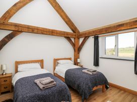 A bedroom with two single beds wooden beams on ceiling and window with curtains at Yr Adfa in Llangeitho near Tregaron