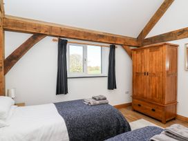 A bedroom with two beds a wooden wardrobe and a window with black curtains at Yr Adfa Llangeitho near Tregaron