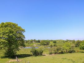 A rural landscape with green fields trees and a pond under a clear blue sky at Yr Adfa in Llangeitho near Tregaron