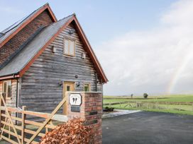 A wooden house with a brick pillar and gate on a paved driveway with green fields and a rainbow in the background at White House in Montgomery