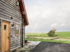 A wooden house with a door and window next to a paved driveway and green fields in the background at White House Montgomery