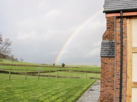 A grassy field with a wooden fence and a rainbow in the sky beside a brick house at White House in Montgomery