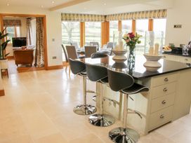 A kitchen area with a black countertop island and bar stools next to a dining table set near large windows at White House in Montgomery