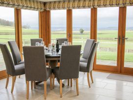 A dining area with a round table set for six and large windows overlooking green fields at White House in Montgomery
