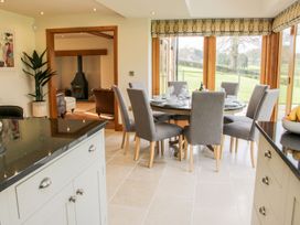A dining area with a round table and gray chairs near large windows showing a green outdoor area at White House in Montgomery