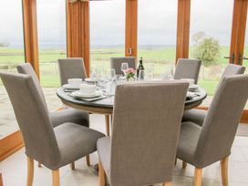 A dining area with a round table set with dishes and glasses surrounded by six gray upholstered chairs at White House in Montgomery