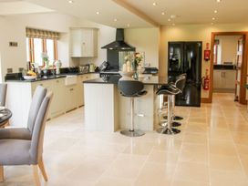 A kitchen with an island and bar stools next to a black refrigerator and dining chairs at White House Montgomery