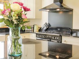 A kitchen with flowers in a glass vase on a black countertop near a stove and oven with a kettle and toaster on the counter at White House in Montgomery