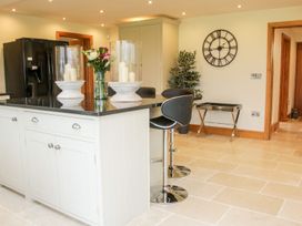 A kitchen with a black countertop island featuring candles and flowers with black bar stools a large clock on the wall and a black refrigerator at White House in Montgomery