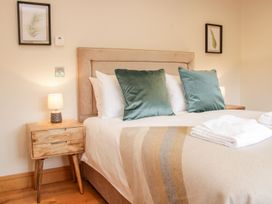 A bedroom with a bed with green pillows a wooden nightstand with a lamp and wall art at White House in Montgomery