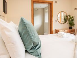 A bedroom with a bed and pillows next to a wooden dresser with a round mirror and plant at White House Montgomery