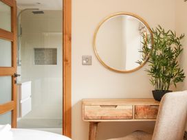 A wooden desk with a round mirror and a potted plant next to a bathroom with a glass shower door at White House in Montgomery