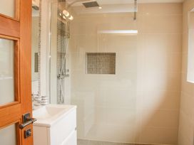 A bathroom with a white sink vanity wooden door glass shower enclosure and tiled walls at White House in Montgomery