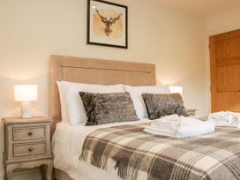 A bedroom with a bed with fur pillows a checkered blanket two bedside tables with lamps and a deer painting above the bed at White House Montgomery