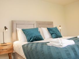 A bed with two teal pillows white linens a folded towel set on a blue patterned blanket and wooden nightstands with lamps at White House in Montgomery