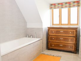 A bathroom with a bathtub beside a wooden chest of drawers under a window at White House in Montgomery