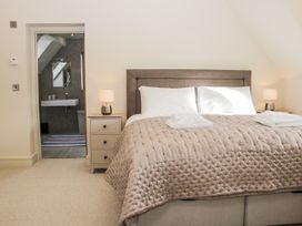 A bedroom with a double bed covered with a quilt and pillows bedside tables with lamps and an open door leading to a bathroom at White House in Montgomery