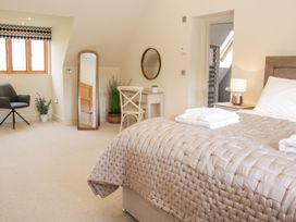 A bedroom with a bed covered with a quilt and towels a chair a mirror a desk with a chair plants and a bedside table with a lamp at White House in Montgomery