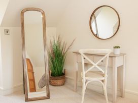 A corner with a standing mirror a potted plant a round wall mirror a desk with drawers a chair and a small plant on the desk at White House Montgomery