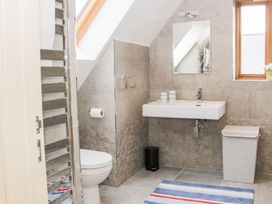 A bathroom with a toilet a wall-mounted sink a mirror a window a towel radiator a laundry basket and a striped rug at White House in Montgomery