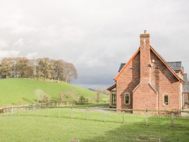 A brick house with a chimney next to a fenced grassy area and a hill with trees in the background at White House in Montgomery