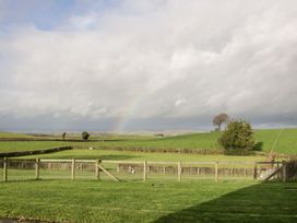 Green fields with trees and a fence under a cloudy sky with a faint rainbow at White House in Montgomery