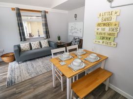A dining area with a set table and a living space with a couch and armchair in the background at Chalet 22 in Port Eynon
