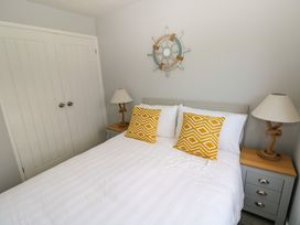 A bedroom with a bed with two yellow patterned pillows two bedside tables with lamps and a wall decoration above the headboard at Chalet 22 in Port Eynon