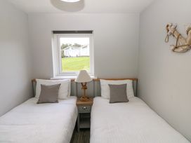 A bedroom with two single beds separated by a nightstand with a lamp under a window and a decorative anchor on the wall at Chalet 22 in Port Eynon