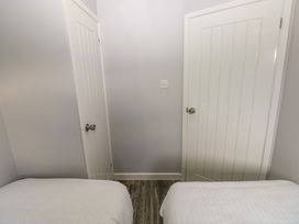 A bedroom with two beds a wooden floor and two white paneled doors at Chalet 22 in Port Eynon