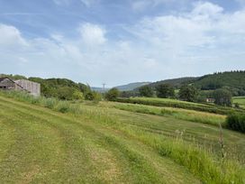 A view of grass and hills with a wooden building at Cottage 1 in Presteigne