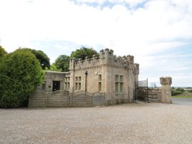 A castle-like stone building with a wooden fence and gravel driveway at Walworth Castle Lodge in Walworth near Darlington