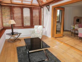 A room with wooden blinds a floral armchair a black glass coffee table a floor lamp and wooden folding doors at Walworth Castle Lodge in Walworth near Darlington