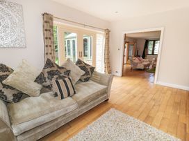 A living room with a cushioned sofa and patterned pillows hardwood floor and a view into another room with chairs at Walworth Castle Lodge in Walworth near Darlington