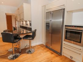 A kitchen with a stainless steel refrigerator an oven black countertop and three black bar stools at Walworth Castle Lodge in Walworth near Darlington