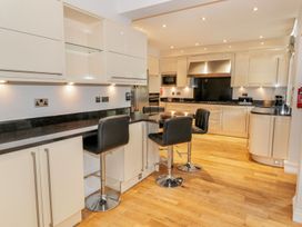 A kitchen with black countertops black bar stools wooden floor and white cabinets at Walworth Castle Lodge in Walworth near Darlington