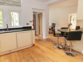 A kitchen area with a black countertop and cream cabinets next to a black round table with three black chairs and wooden flooring at Walworth Castle Lodge in Walworth near Darlington