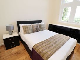 A bedroom with a double bed featuring plaid cushions and a throw blanket a bedside table with a lamp and built-in drawers under the window at Walworth Castle Lodge in Walworth near Darlington